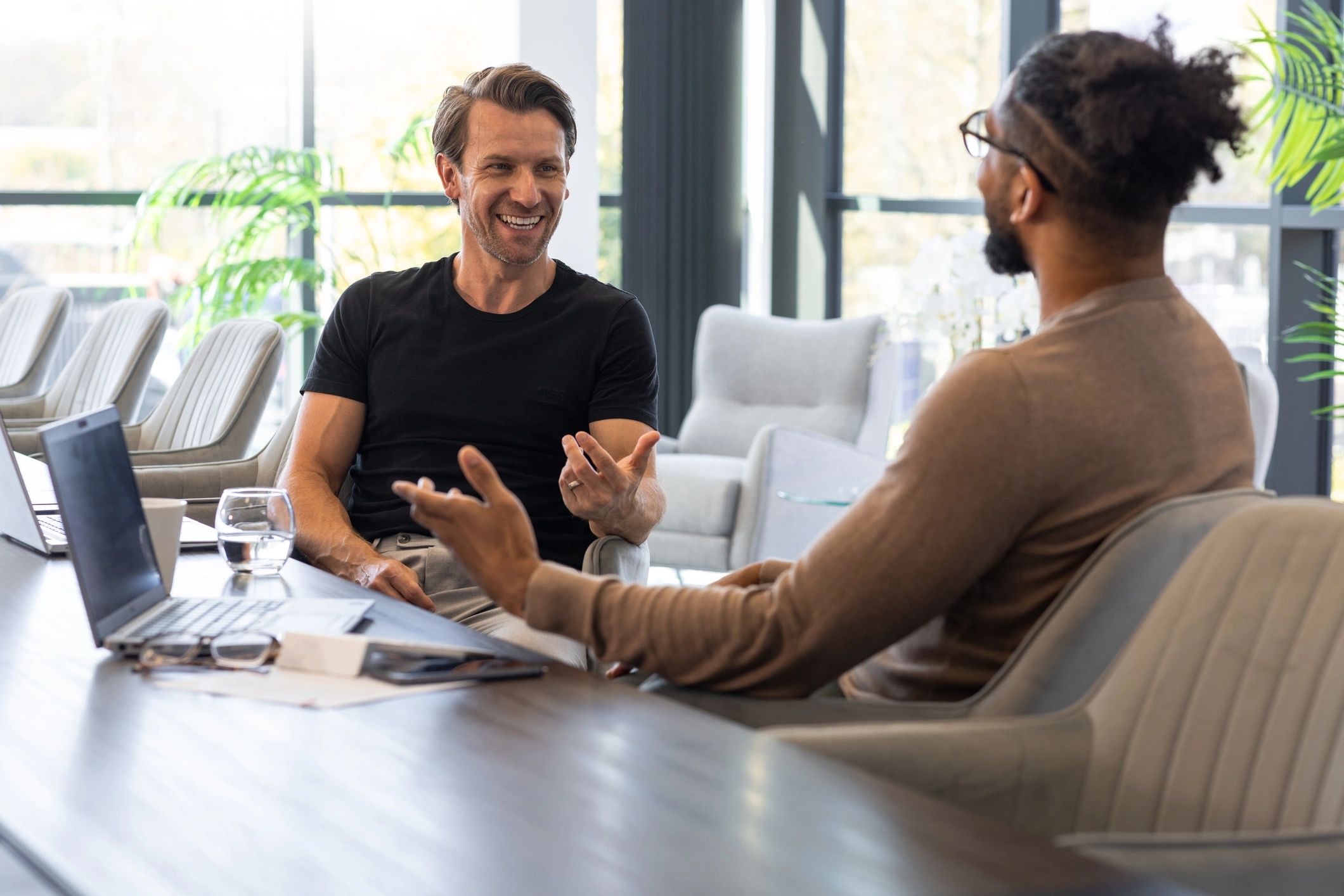 Two professionally dressed men sitting in a conference room attending a meeting